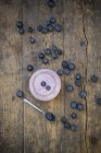 Fresh Blueberries and glass of blueberry yoghurt on dark wood — Stock Photo
