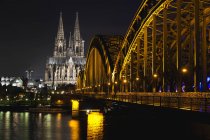 Germany, North Rhine-Westphalia, Cologne, Cathedral and Hohenhollern Bridge over the Rhine river illuminated in night — Stock Photo