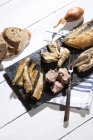 Різноманітність мариновану і мариновані риби на Шифер на білий дерев'яний стіл з хлібом — стокове фото
