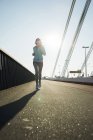 Jovem jogger feminino em movimento em uma ponte — Fotografia de Stock