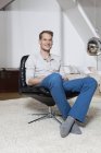 Homme à la maison relaxant dans un fauteuil — Photo de stock
