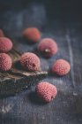 Fresh Lychees on dark wooden table with bark — Stock Photo