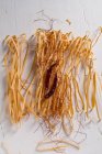 Elevated view of uncooked chili pasta, chili pod and chili threads on white wooden table — Stock Photo