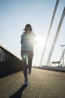 Jovem jogger feminino em movimento em uma ponte — Fotografia de Stock