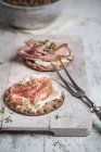 Round crispbreads, cream cheese, cooked ham, gammon and cress on chopping board with fork — Stock Photo
