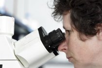 Scientist looking through microscope — Stock Photo