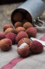 Litchis and metal cup on rustic cloth — Stock Photo