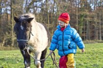 Little girl walking with pony on a meadow — Stock Photo