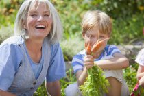 Mature woman and boy inspecting carrots in garden — Stock Photo