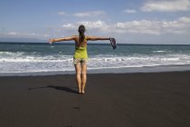 Jeune femme debout sur sable noir — Photo de stock