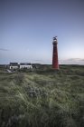 Netherlands, illuminated lighthouse with buildings at dusk — Stock Photo