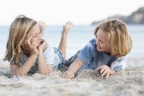 Bambini sdraiati nella sabbia sulla spiaggia — Foto stock