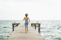 Ragazzo che corre sul molo al mare — Foto stock