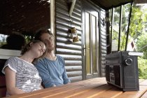 Hombre y mujer escuchando la radio en casa de campo en el jardín de la parcela - foto de stock