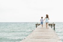 Ragazza e ragazzo in esecuzione sul molo — Foto stock