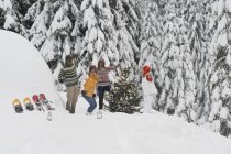 Hombres y mujeres bailando junto al árbol de Navidad - foto de stock