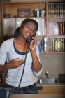 Молода жінка, відповідаючи на телефоні в офісі, посміхаючись — стокове фото