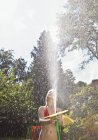 Girl spraying water with garden hose — Stock Photo