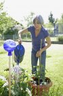 Mujer mayor regando plantas en el jardín - foto de stock