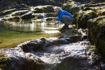Austria, Land Salisburgo, Faistenau, Donna matura che beve acqua dal fiume — Foto stock