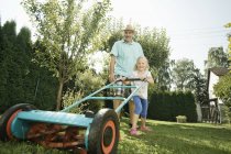 Avô com filhos cortando gramado — Fotografia de Stock