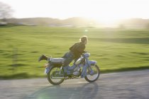 Donna matura cavalcando vecchio ciclomotore del 1960 — Foto stock
