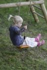 Девушка играет на качелях — стоковое фото