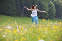 Jovem mulher correndo no campo de flores — Fotografia de Stock