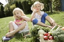 Girls eating vegetables in garden — Stock Photo