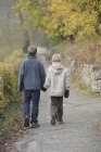 Brother and sister walking on footpath in autumn — Stock Photo