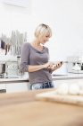 Femme utilisant mobile dans la cuisine — Photo de stock