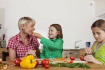 Madre e hijos cortando verduras - foto de stock