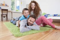 Smiling Family relaxing on floor and looking at camera — Stock Photo