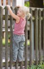 Chica de pie en la valla de madera - foto de stock