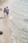 Casal sênior andando ao longo da praia de mãos dadas — Fotografia de Stock