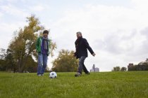 Hombres jugando al fútbol en el parque, sonriendo - foto de stock