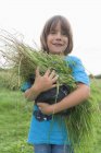 Niño sosteniendo manojo de hierba en el jardín - foto de stock