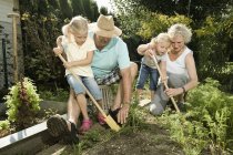 Abuelos con niños trabajando en el jardín - foto de stock