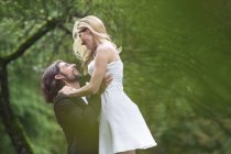 Felice sposo sollevamento sposa in giardino — Foto stock