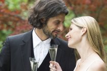 Felice sposa e sposo con bicchieri di champagne in giardino — Foto stock