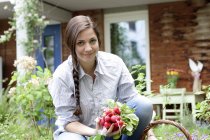 Junge Frau mit roten Radieschen im Gemüsegarten — Stockfoto