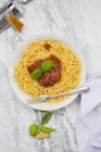 Plate of Spaghetti Bolognese, cloth, parmesan and basil leaves on white marble, elevated view — Stock Photo