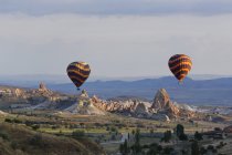 Turquía, Anatolia Oriental, Capadocia, dos globos aerostáticos flotando sobre formaciones rocosas de toba en el Parque Nacional Goereme - foto de stock