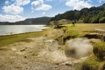 Portugal, Azores, Sao Miguel, Caldeiras en Lagoa das Furna y la costa de hierba verde contra el agua - foto de stock