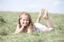 Cute young lying on meadow with hay — Stock Photo