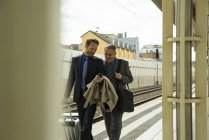 Deux hommes d'affaires marchant et parlant à la gare — Photo de stock