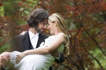 Felice celebrazione, Sposo che porta sposa in giardino — Foto stock