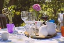 Glasses, cups and espresso can on garden table — Stock Photo