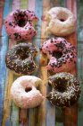 Six bitten mini doughnuts on coloured wood — Stock Photo