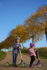 Мальчик и девочка стоят на улице со скутерами и шлемами — стоковое фото